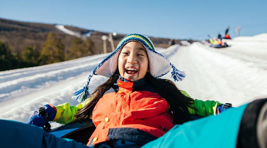 A joyful child enjoying winter tubing at Camelback Snow Park, part of the top-rated Camelback ski and tube experience in the Poconos. Perfect for family fun at Pennsylvania’s favorite PA ski destination, offering exciting snow park activities and Poconos snow adventures for all ages.