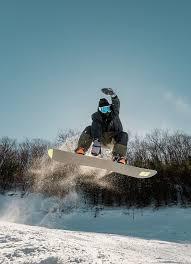 Snowboarder performing a jump at Camelback Resort in the Poconos, surrounded by snowy mountain trails. The image captures the thrill of Poconos snowboarding and skiing adventures, showcasing Camelback’s winter sports excitement and mountain resort atmosphere.