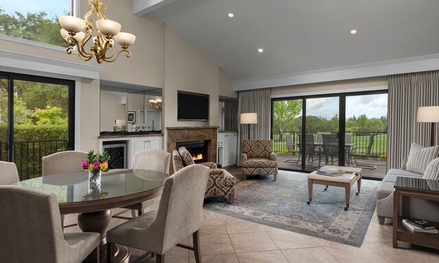 Elegant and spacious Historic Mansion Residence at Silverado Resort featuring a beautifully furnished living area with a fireplace, modern decor, and large windows that open to a private balcony overlooking lush green views — showcasing classic Napa Valley charm just steps from everything.