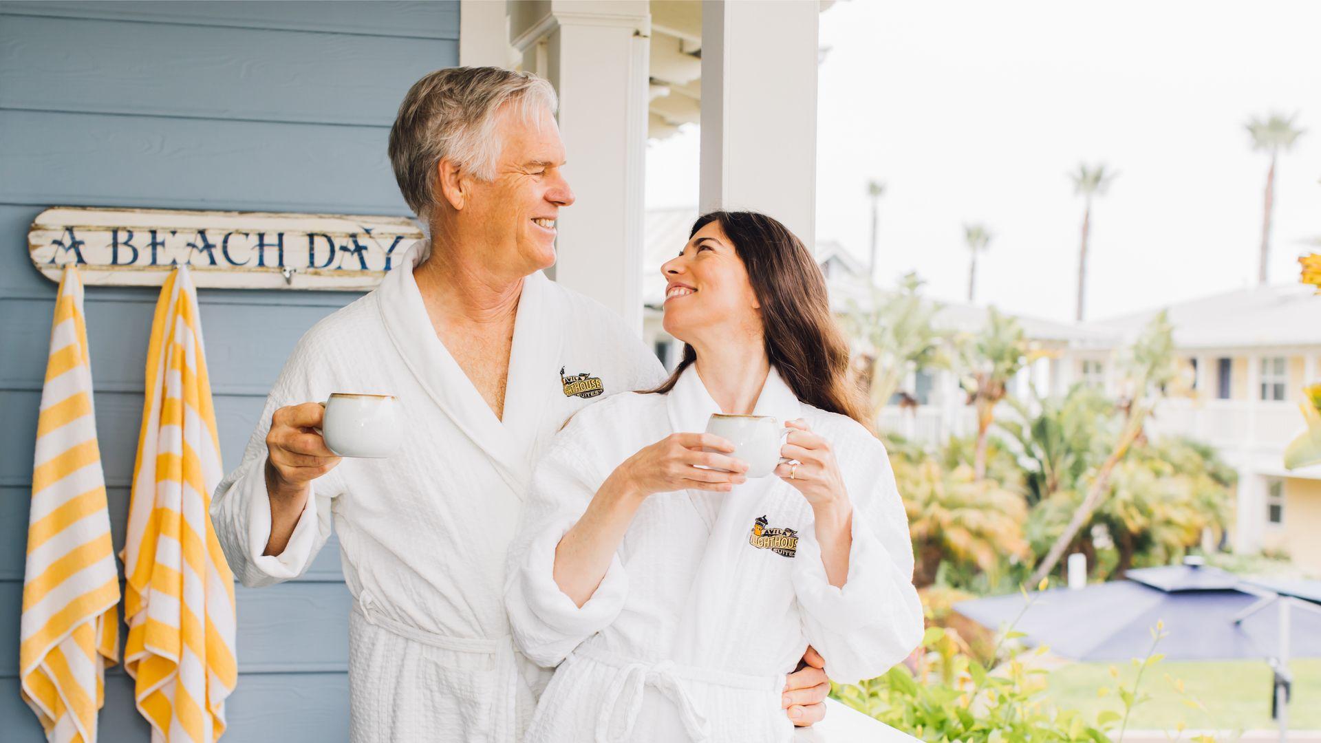 A happy couple enjoying morning coffee in cozy robes on a balcony at Avila Lighthouse Suites, surrounded by palm trees and coastal views – Plan Your Dream Avila Beach Escape Today.A happy couple enjoying morning coffee in cozy robes on a balcony at Avila Lighthouse Suites, surrounded by palm trees and coastal views – Plan Your Dream Avila Beach Escape Today.