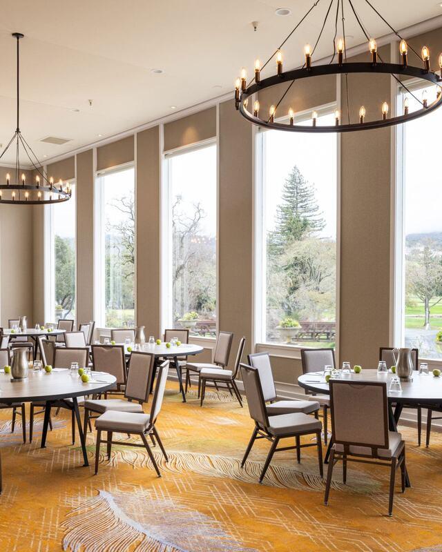"Diverse Suite Options: Perfectly Sized for Every Celebration — a beautifully lit event space featuring elegant round tables, soft neutral tones, and expansive windows overlooking lush Napa Valley landscapes. This sophisticated setting at Silverado Resort combines comfort and versatility, making it ideal for weddings, meetings, and private gatherings in California wine country."