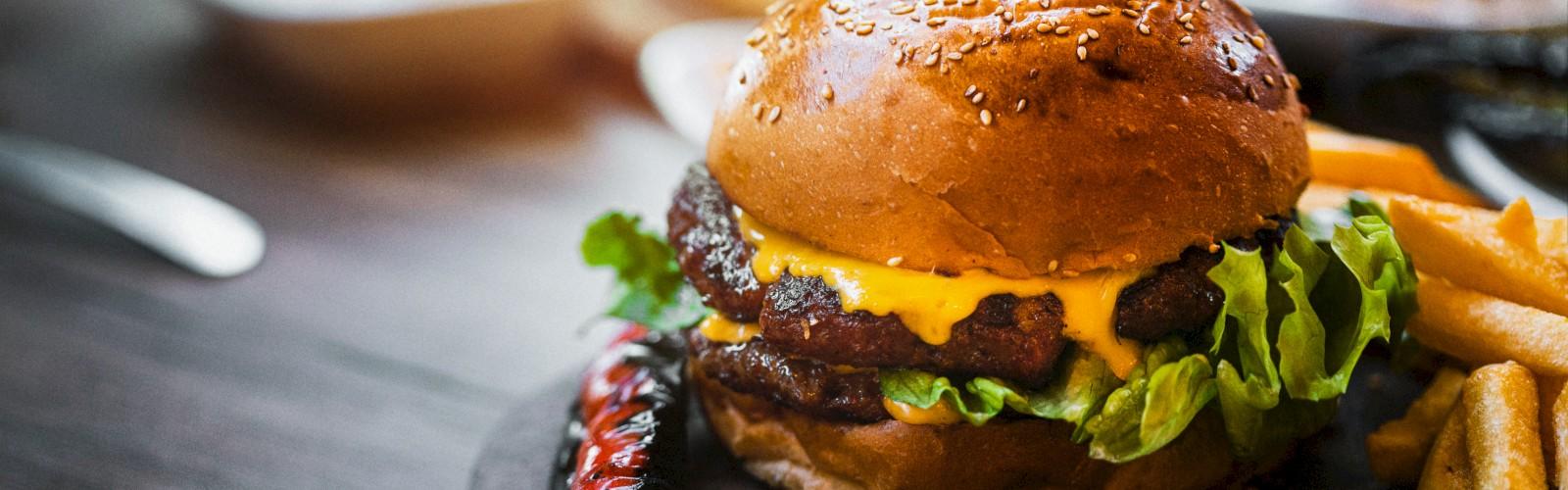 Juicy cheeseburger with fresh lettuce and golden fries served at Tropics Restaurant — your daily destination for fresh, flavorful dining and all-day casual elegance with stunning views at Saddlebrook Resort.